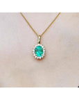 Oval 3.01 ct natural emerald pendant with halo diamonds on an 18K yellow gold chain.
