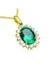 A 18k yellow gold pendant with an oval cut natural colombian emerald with a halo diamond, topside view.