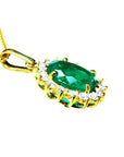 Oval natural emerald pendant with halo diamonds in 18K yellow gold.