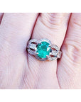 Natural oval emerald ring in 18K white gold with a decorative, bridal-style band.