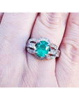 Natural oval emerald ring in 18K white gold with a decorative, bridal-style band.