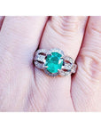 Natural oval emerald ring in 18K white gold with a decorative, bridal-style band.