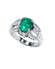 Natural oval emerald ring in 18K white gold with a decorative, diamond-accented band.