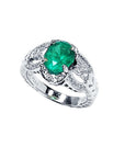 Natural oval emerald ring in 18K white gold with a decorative, diamond-accented band.