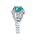 Natural oval emerald ring in 18K white gold with decorative bridal-style band and diamond accents.