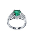 Natural oval emerald ring in 18K white gold with a decorative, bridal-style diamond band.