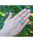 Oval 2.02 ct deep green emerald halo ring with diamonds on a hand, 14K white gold.