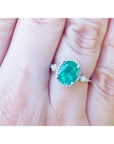 14K white gold halo ring with a 2.02 ct. oval-cut deep green emerald and natural diamonds.