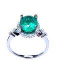A natural oval emerald ring with accent diamonds in white gold, top and lateral view.