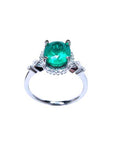 A natural oval emerald ring with accent diamonds in white gold, top and lateral view.