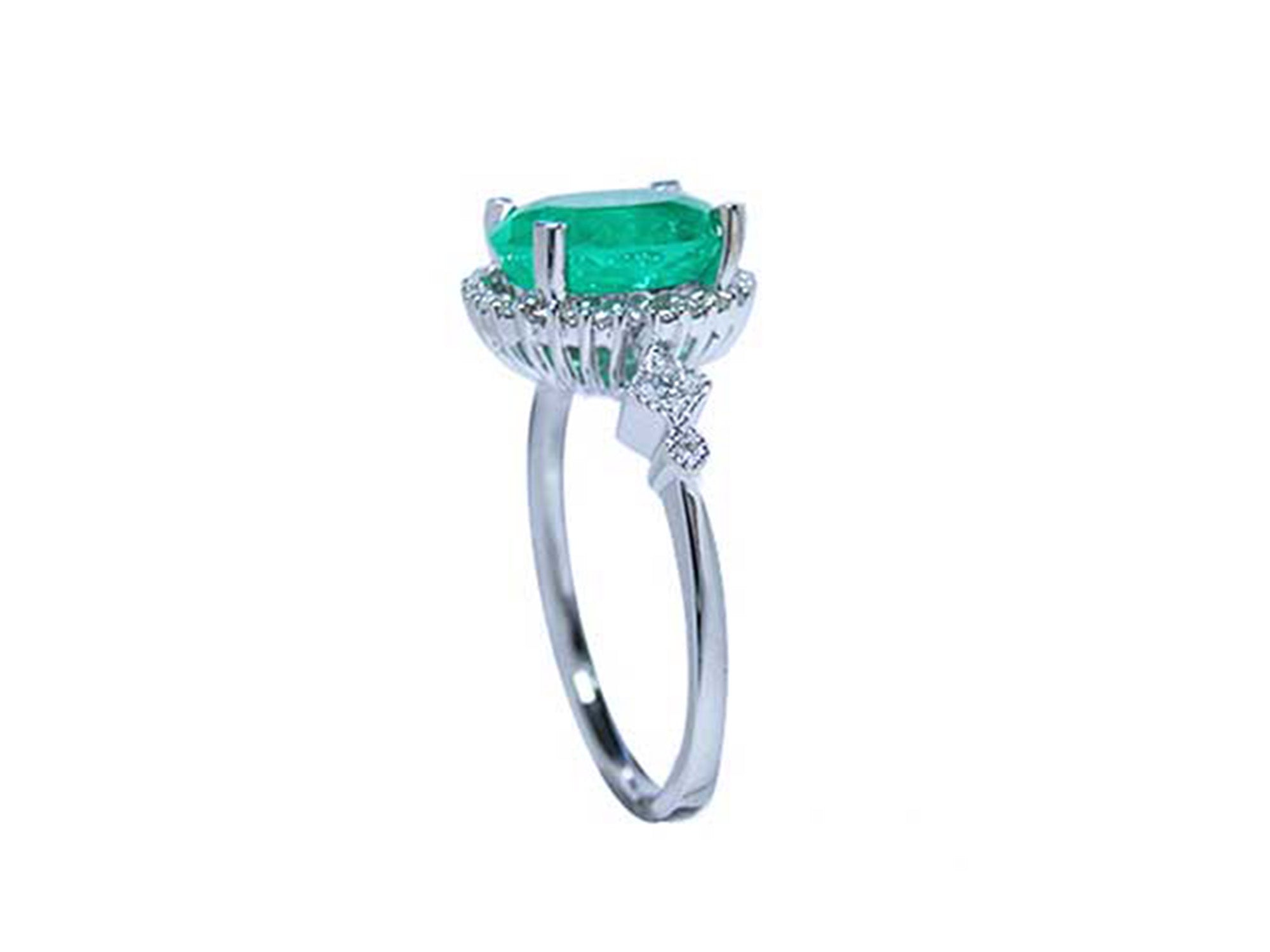 An emerald ring displaying the top side gallery and band with accent diamonds.