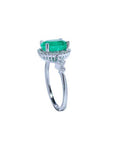 An emerald ring displaying the top side gallery and band with accent diamonds.