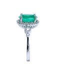 Emerald ring with diamond accents on a white background