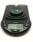 Two oval-cut, deep bluish-green natural emeralds weighing 1.60 cttw on a black digital scale.