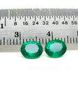 Two oval-cut natural emeralds, deep bluish-green, next to a ruler, 1.60 cttw.