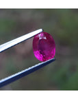 1.31 ct. natural Burma ruby, oval cut, vivid red, held by silver tweezers.