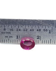 Oval cut ruby loose natural gemstone from Burma, front side crown and table visibles on a ruler for scale