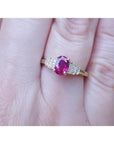 Women's 14k yellow gold ring with a deep red oval ruby and sparkling side diamonds.