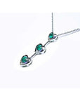14K white gold heart journey pendant necklace with three round Colombian emeralds.