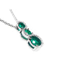 14K white gold emerald journey pendant with three round-cut Colombian emeralds and diamond accents.
