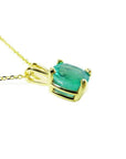 Cushion cut natural emerald solitaire pendant in 14K yellow gold with four-prong setting.