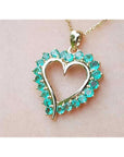 Heart-shaped pendant with round cut colombian emerald stones made of 14k yellow gold.