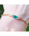 14k gold paperclip bracelet with a natural colombian emerald and accent diamonds on a wrist.