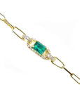 The lateral side view of a gold paperclip bracelet with a Muzo colombian emerald and diamonds.