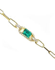 The lateral side view of a gold paperclip bracelet with a Muzo colombian emerald and diamonds.