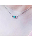 0.68 ct paper clip emerald necklace with diamonds in 18K white gold on a woman's neck.