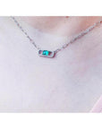 0.68 ct paper clip emerald necklace with diamonds in 18K white gold on a woman's neck.