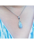 Pear-shaped Australian opal pendant with halo diamonds on an 18K white gold chain, worn on a person.