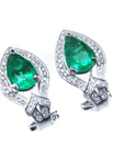 Pair of emerald green teardrop earrings with white gold detailing on a white background