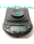 1.74-carat pear-cut Colombian emerald on a digital scale, with other emeralds in the background.