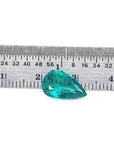 2.65 carat pear cut loose Colombian emerald with vibrant medium deep green hue next to a ruler.