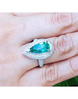 A USA made women’s emerald ring pear shaped, between a woman's fingers.