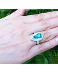 Pear-shaped 3.35 ct. emerald engagement ring in 14K white gold with diamond halo on a hand.