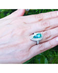 Pear-shaped 3.35 ct. emerald engagement ring in 14K white gold with diamond halo on a hand.