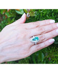 Pear-shaped 3.35 ct. emerald engagement ring in 14K white gold with diamond halo on a hand.