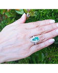 Pear-shaped 3.35 ct. emerald engagement ring in 14K white gold with diamond halo on a hand.