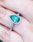 Teardrop-shaped emerald ring on a hand.