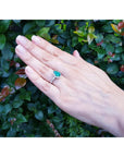 1.43 ct teardrop emerald engagement ring in 14K white gold with diamond halo on a hand.