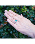 1.43 ct teardrop emerald engagement ring in 14K white gold with diamond halo on a hand.