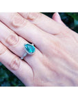 1.43 ct teardrop emerald engagement ring in 14K white gold with diamond halo on a hand.