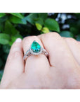 1.43 ct teardrop emerald engagement ring in 14K white gold with diamond halo on a hand.