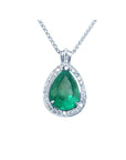 Emerald teardrop pendant with diamond halo on a topside view.