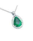 Teardrop-shaped emerald pendant with diamond accents on a topside view.