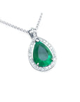 Teardrop-shaped emerald pendant with diamond accents on a topside view.