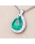 Green emerald pendant with white gold chain on beige skin background