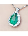 Green emerald pendant with white gold chain on beige skin background